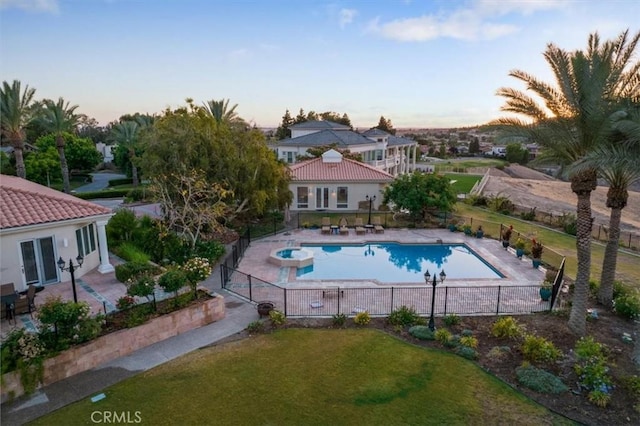 pool at dusk with a yard and a patio