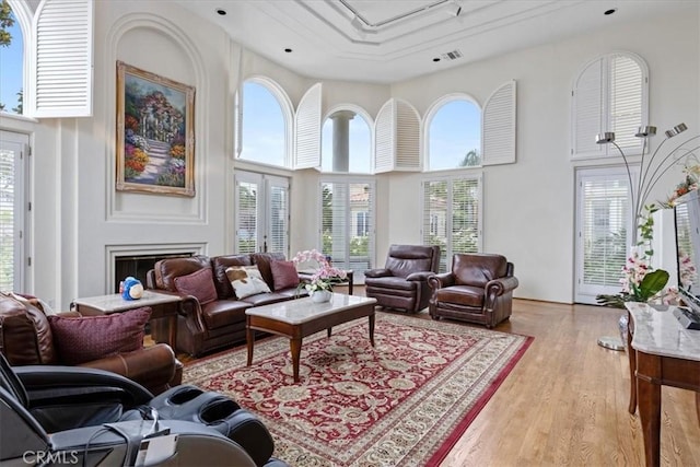 living room featuring a high ceiling, plenty of natural light, and light hardwood / wood-style flooring