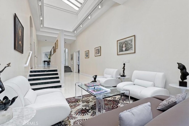 living room featuring a skylight, track lighting, and a high ceiling