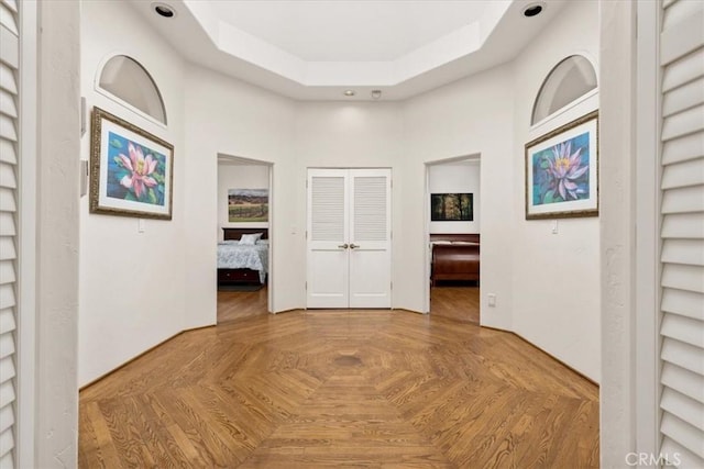 hallway featuring parquet floors and a raised ceiling