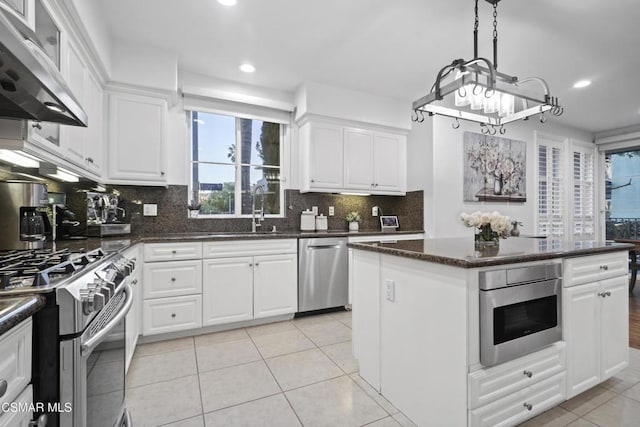 kitchen with sink, stainless steel appliances, white cabinets, a kitchen island, and exhaust hood