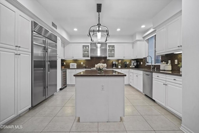 kitchen featuring white cabinetry, appliances with stainless steel finishes, a kitchen island, and wall chimney range hood