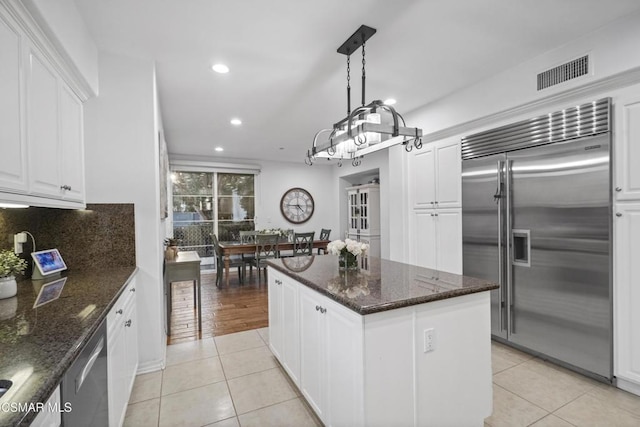 kitchen with light tile patterned flooring, appliances with stainless steel finishes, a center island, and white cabinets