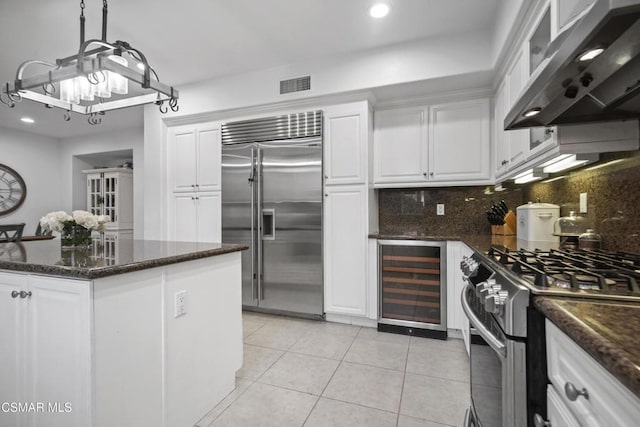 kitchen with white cabinets, stainless steel appliances, beverage cooler, and exhaust hood