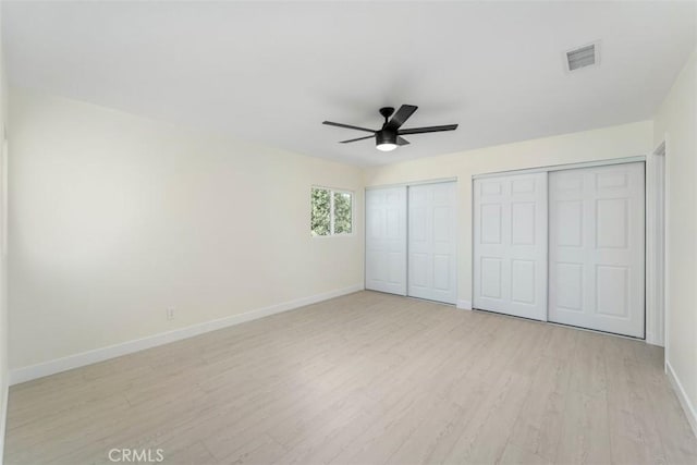 unfurnished bedroom with multiple closets, light wood-type flooring, and ceiling fan