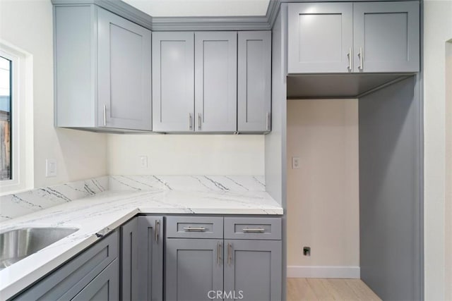 kitchen featuring light stone counters, sink, and gray cabinets