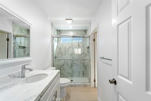 bathroom with an enclosed shower, vanity, hardwood / wood-style floors, and toilet