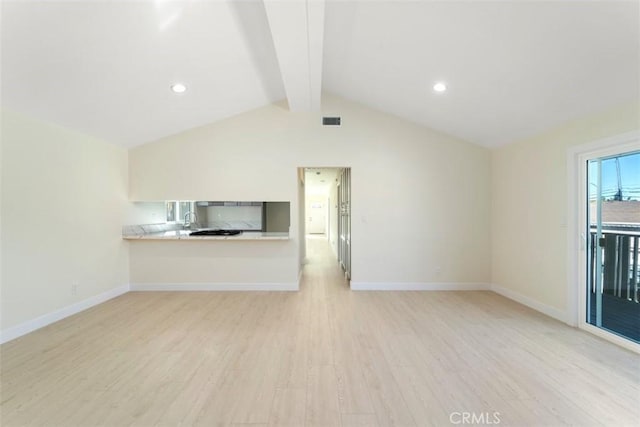 unfurnished living room featuring lofted ceiling with beams, sink, and light hardwood / wood-style flooring