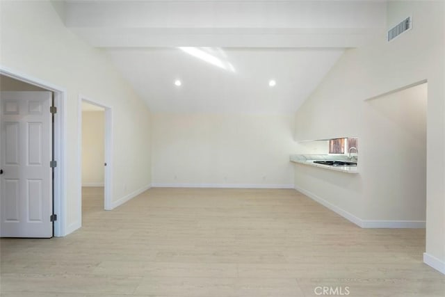 unfurnished room featuring lofted ceiling with beams and light wood-type flooring