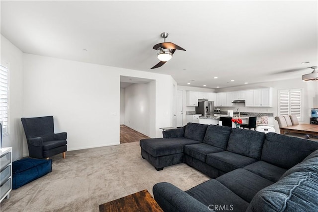 carpeted living room with sink and ceiling fan