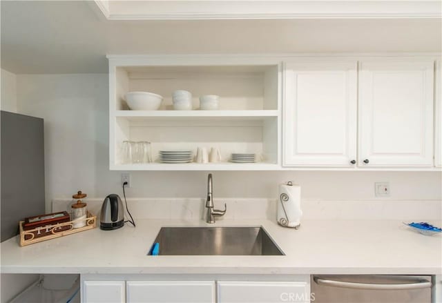 kitchen with white cabinetry, stainless steel dishwasher, sink, and light stone counters