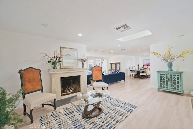 living room featuring a skylight, a premium fireplace, and light hardwood / wood-style flooring