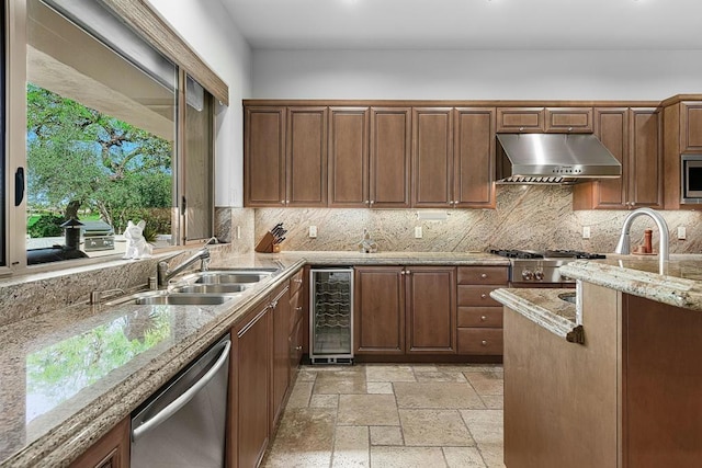 kitchen featuring wine cooler, sink, tasteful backsplash, light stone counters, and appliances with stainless steel finishes