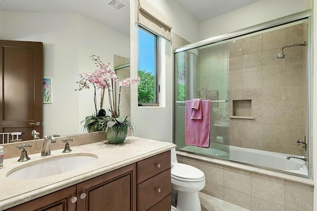 full bathroom featuring enclosed tub / shower combo, vanity, and toilet