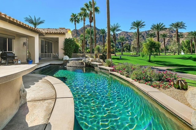 view of swimming pool with a yard, a patio, a grill, a mountain view, and an in ground hot tub