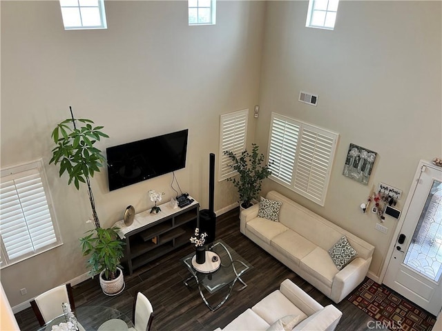 living room with dark wood-type flooring and a high ceiling