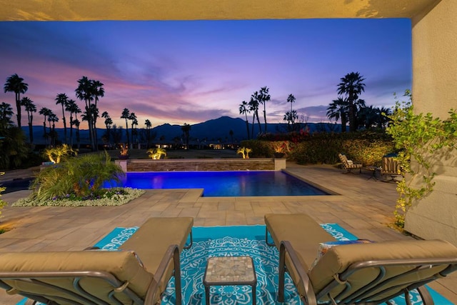 pool at dusk with a mountain view and a patio area