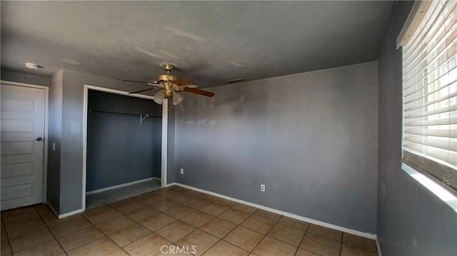 unfurnished bedroom with ceiling fan, tile patterned flooring, and a closet