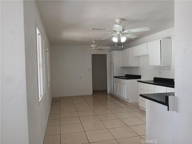 kitchen with dark countertops, visible vents, light tile patterned flooring, ceiling fan, and white cabinetry