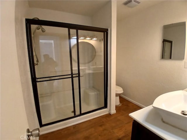 full bath with a stall shower, visible vents, toilet, wood finished floors, and vanity