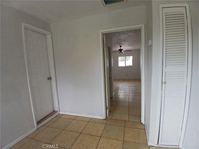 hallway featuring light tile patterned floors, visible vents, and baseboards