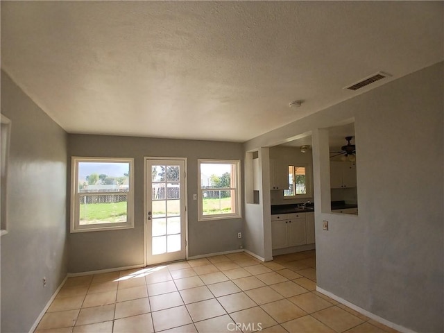 doorway to outside featuring visible vents, a ceiling fan, light tile patterned flooring, a textured ceiling, and baseboards