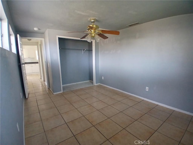 unfurnished bedroom with baseboards, visible vents, a ceiling fan, a closet, and light tile patterned flooring