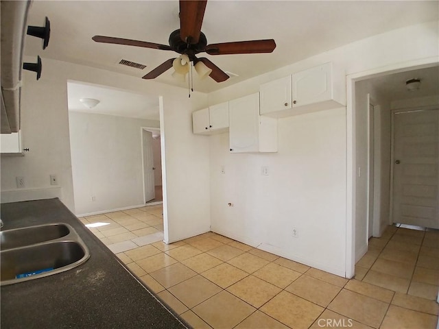 kitchen with light tile patterned floors, a sink, visible vents, white cabinets, and dark countertops