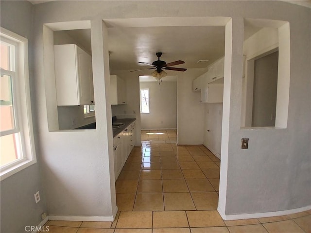 kitchen featuring white cabinets, ceiling fan, baseboards, and light tile patterned floors