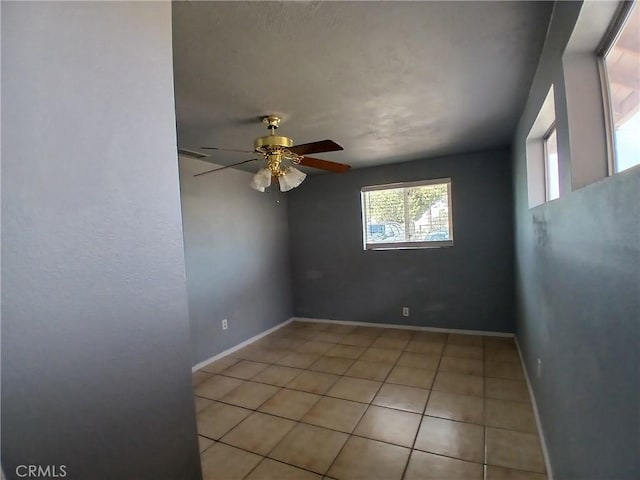 empty room featuring baseboards, a ceiling fan, and light tile patterned flooring