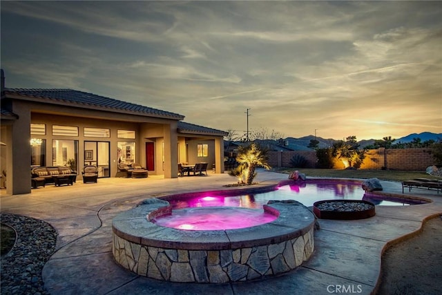 pool at dusk with an outdoor living space, a patio, and an in ground hot tub