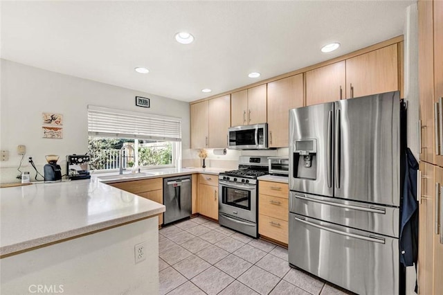 kitchen featuring appliances with stainless steel finishes, sink, light tile patterned floors, and light brown cabinetry