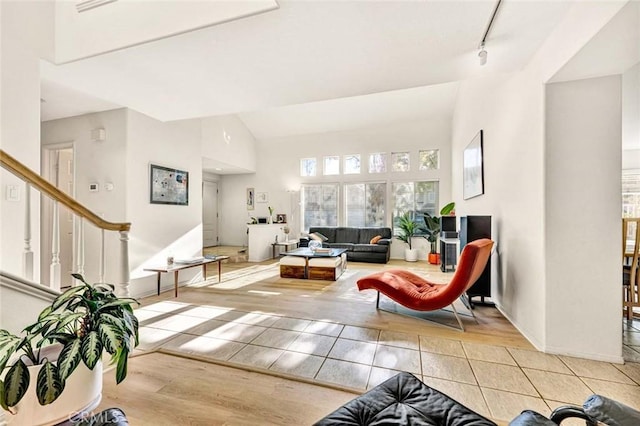 living room featuring track lighting, vaulted ceiling, and light wood-type flooring