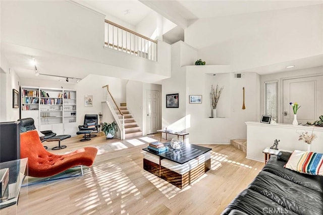 living room with rail lighting, high vaulted ceiling, and light hardwood / wood-style floors