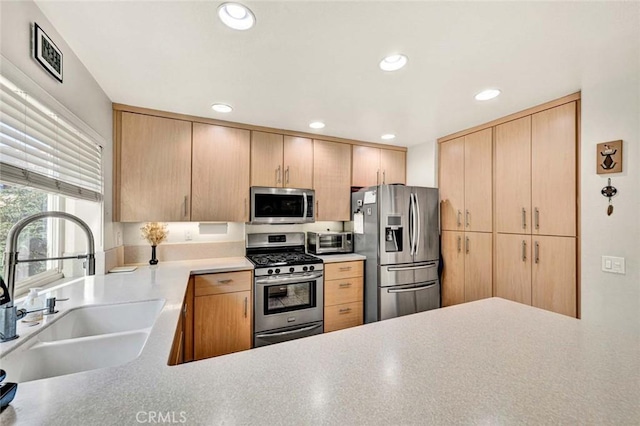 kitchen with appliances with stainless steel finishes, light brown cabinetry, sink, and kitchen peninsula