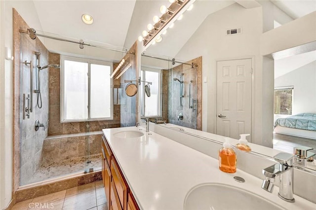 bathroom with tiled shower, vanity, vaulted ceiling, and tile patterned floors