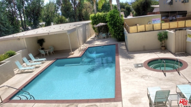 view of swimming pool featuring a hot tub and a patio