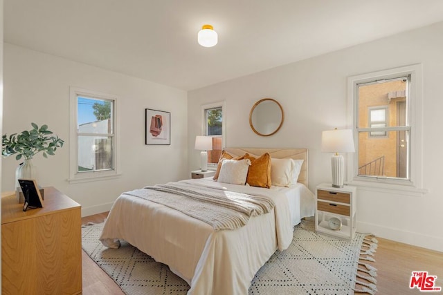 bedroom with multiple windows and light wood-type flooring