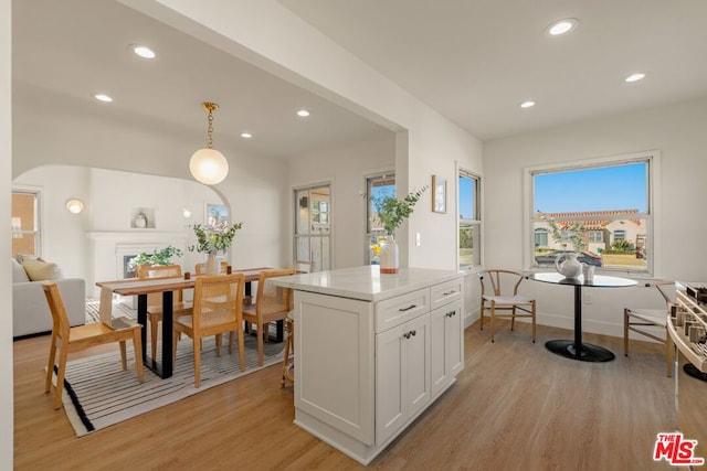 kitchen with white cabinetry, light hardwood / wood-style flooring, and decorative light fixtures