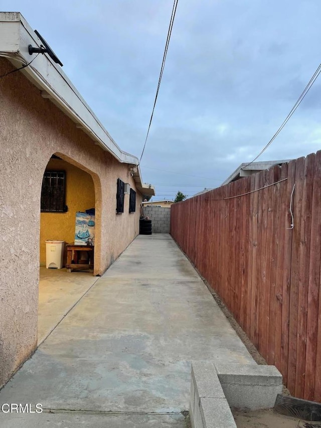 view of side of property with a patio area, fence, and stucco siding