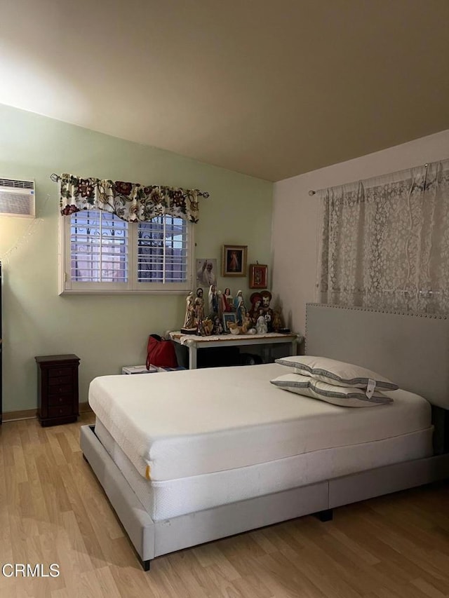 bedroom featuring lofted ceiling, light wood finished floors, and a wall unit AC