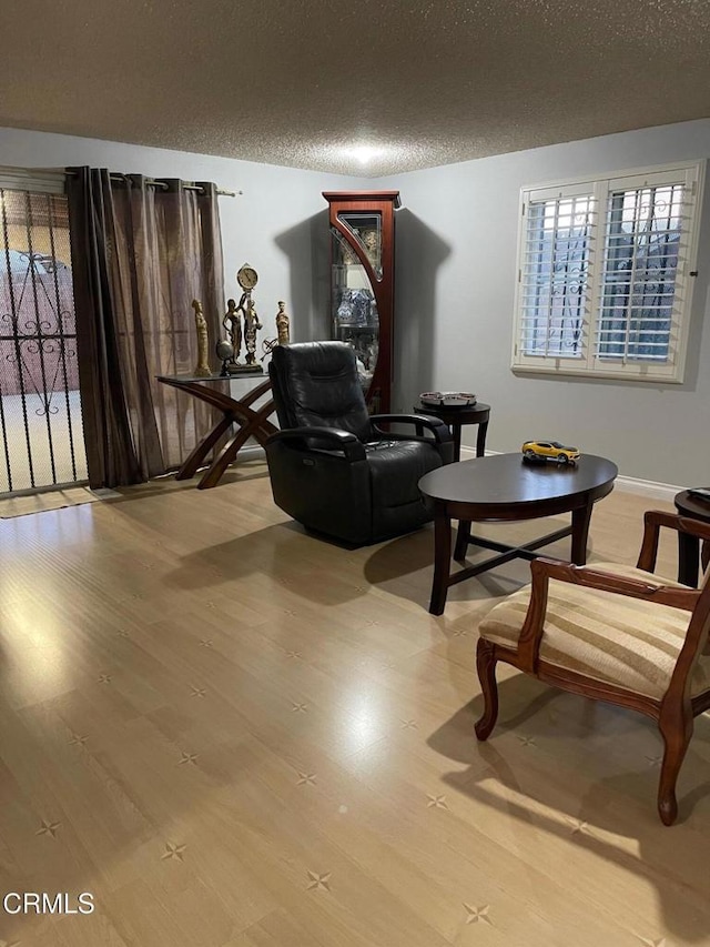 living area with plenty of natural light, a textured ceiling, and wood finished floors