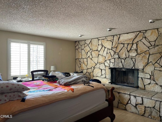 bedroom featuring a fireplace, a textured ceiling, and wood finished floors