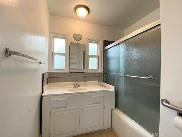 bathroom featuring vanity, shower / bath combination with glass door, and backsplash