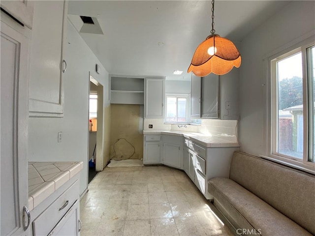 kitchen featuring tasteful backsplash, sink, tile countertops, and decorative light fixtures