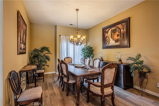 dining space with hardwood / wood-style flooring and an inviting chandelier