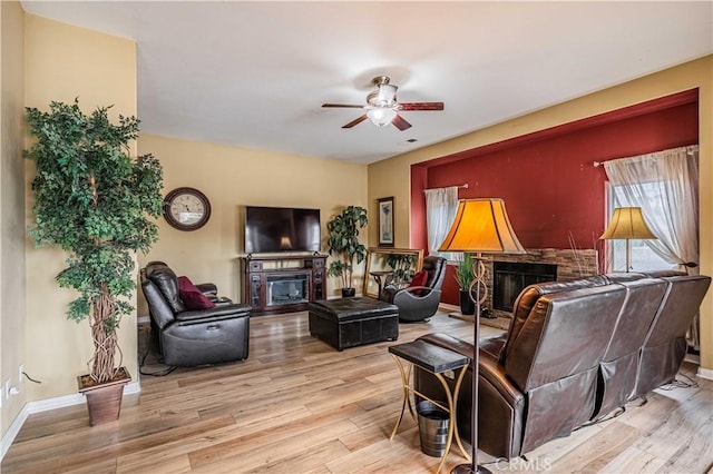 living room with ceiling fan, a fireplace, and light hardwood / wood-style flooring