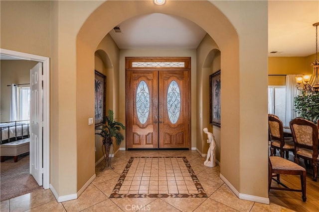 tiled foyer featuring an inviting chandelier