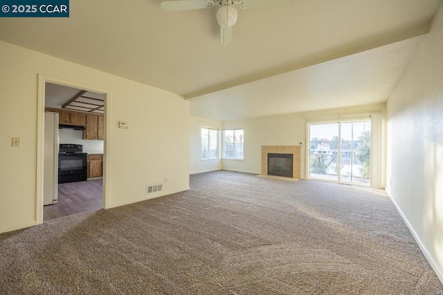 unfurnished living room with a healthy amount of sunlight, a fireplace, and dark carpet