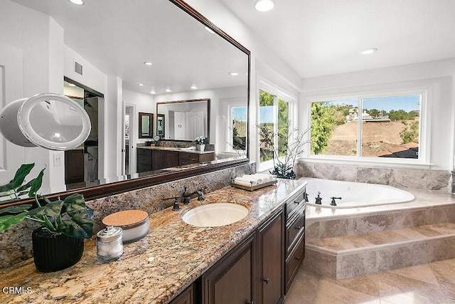 bathroom featuring tiled tub and vanity